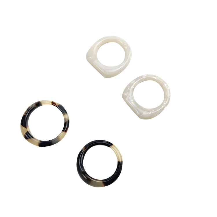 Four rings in pale pearl and tortoiseshell patterns on a white background