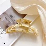 Curved cellulose acetate hair claw clip in an ivory and gold-fleck pattern