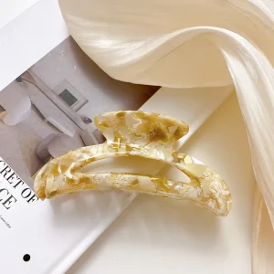 Curved cellulose acetate hair claw clip in an ivory and gold-fleck pattern