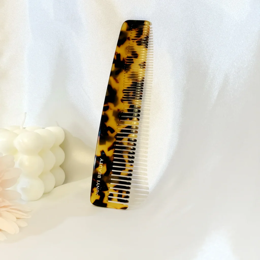 Tortoiseshell cellulose acetate comb with fine and wide teeth on a light display background