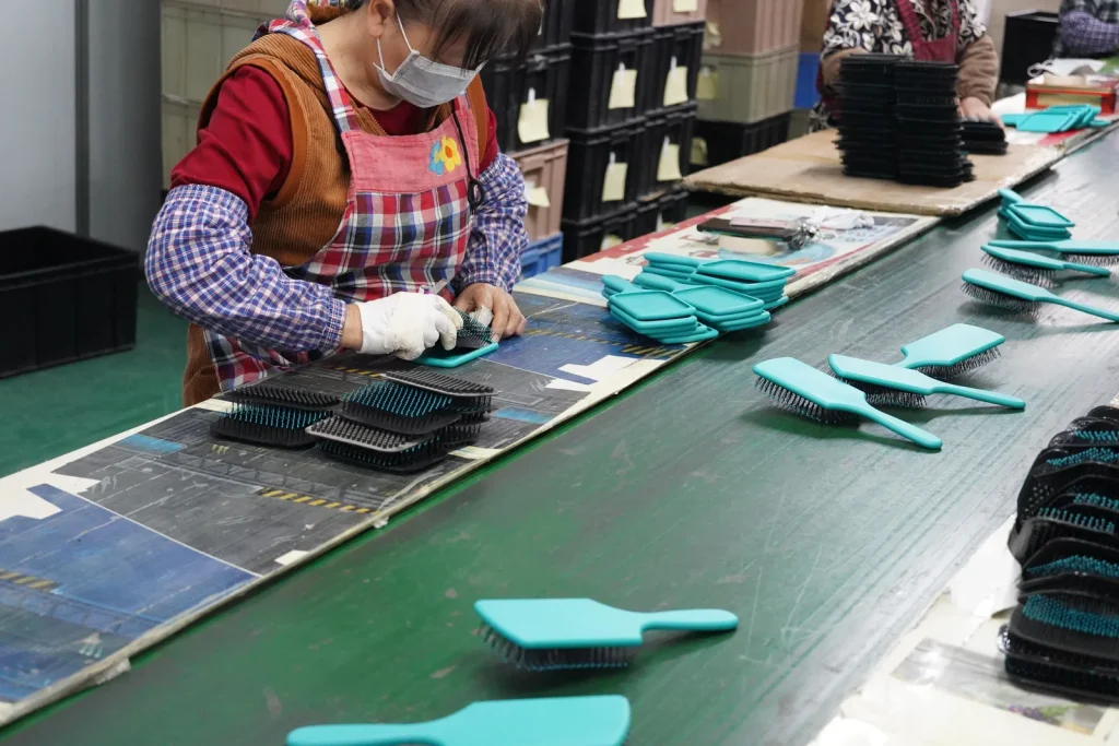 Brush cushion being fitted during hairbrush assembly