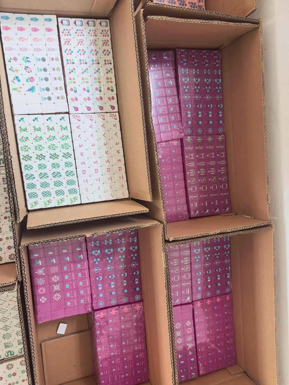 Open cartons containing white and pink mahjong tile sets